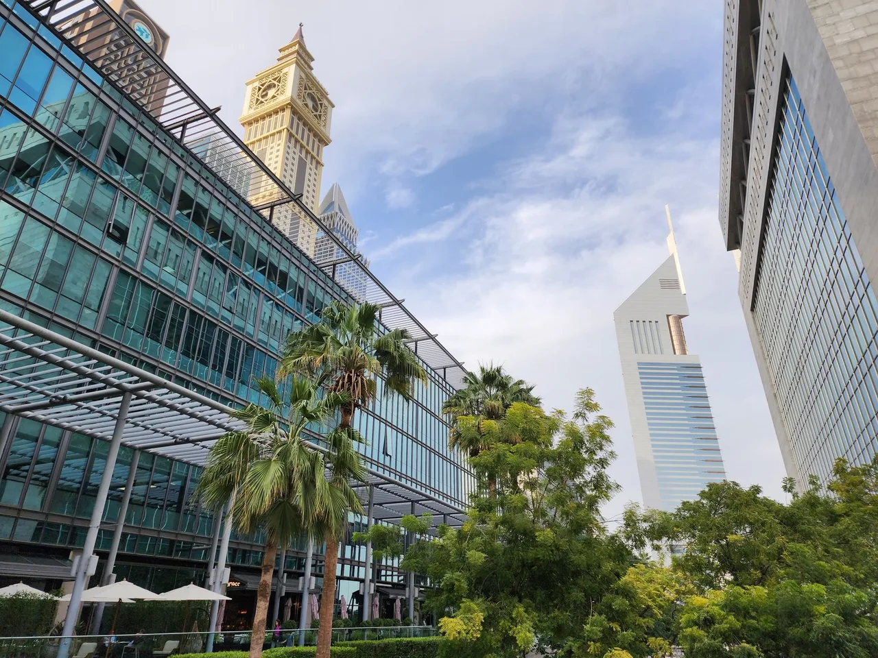 Mrakodrapy Emirates Towers a palmy v obchodní čtvrti Dubaje za dne