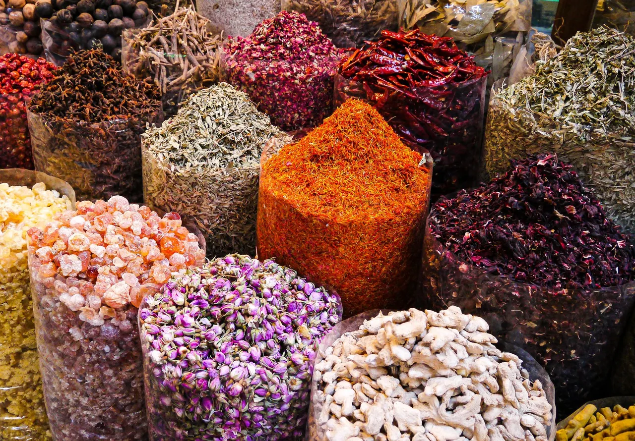 Pestrobarevné hromady sušeného koření a sušených květů na Spice Souku v Deiře