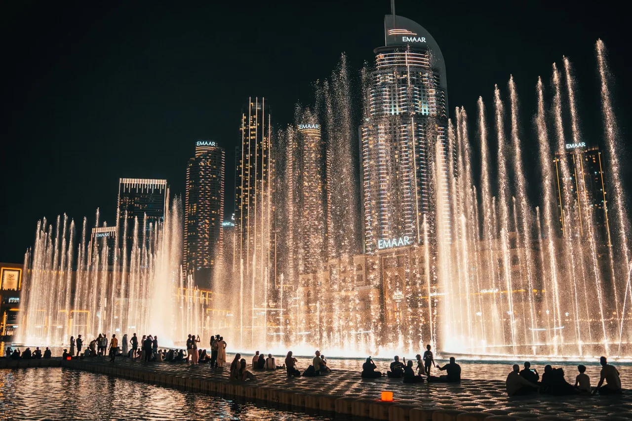 Dubai Fountain: Kompletní průvodce tančící fontánou u Burj Khalifa Tančící Dubai Fountain a diváci na promenádě před mrakodrapy Downtownu