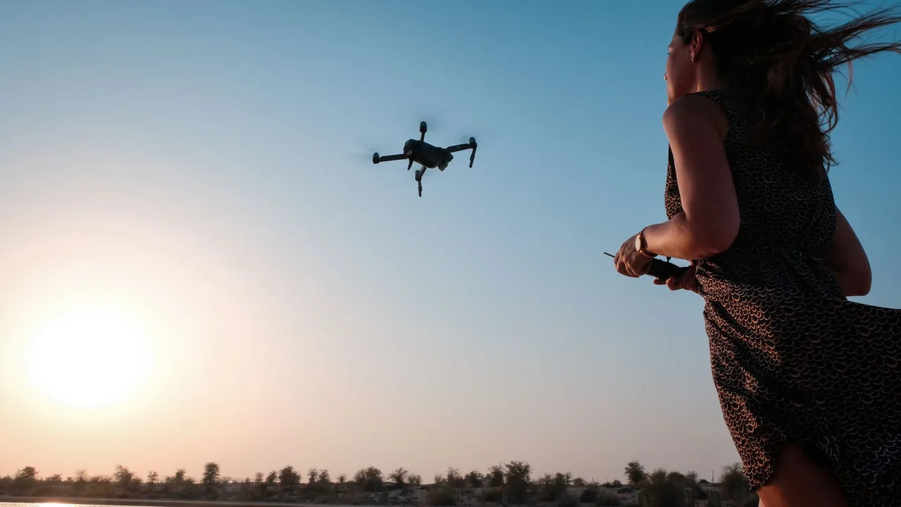 Žena ovládá dron při západu slunce v dubajské poušti