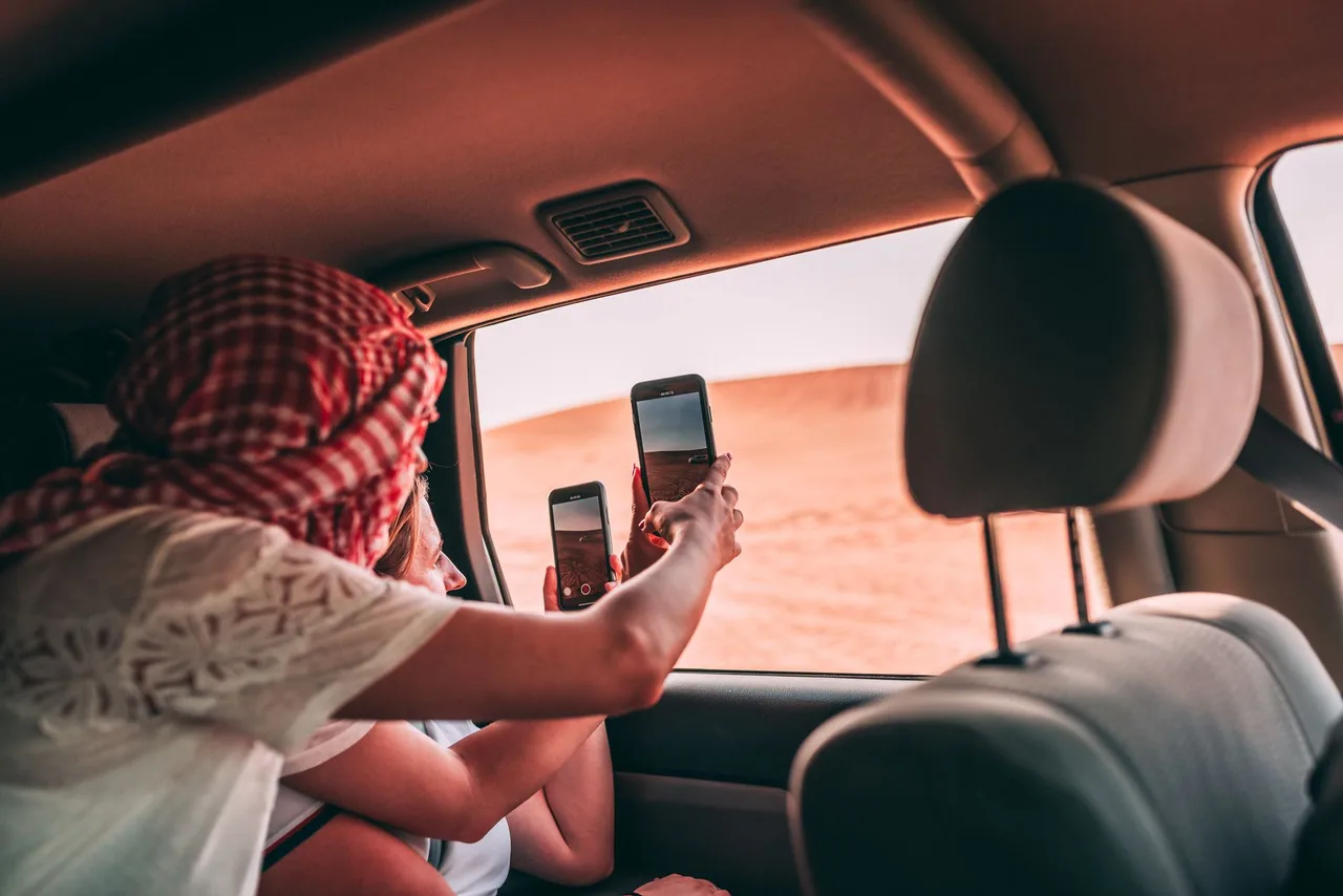 Turisté fotí pouštní krajinu z okna vozu během safari v Dubaji