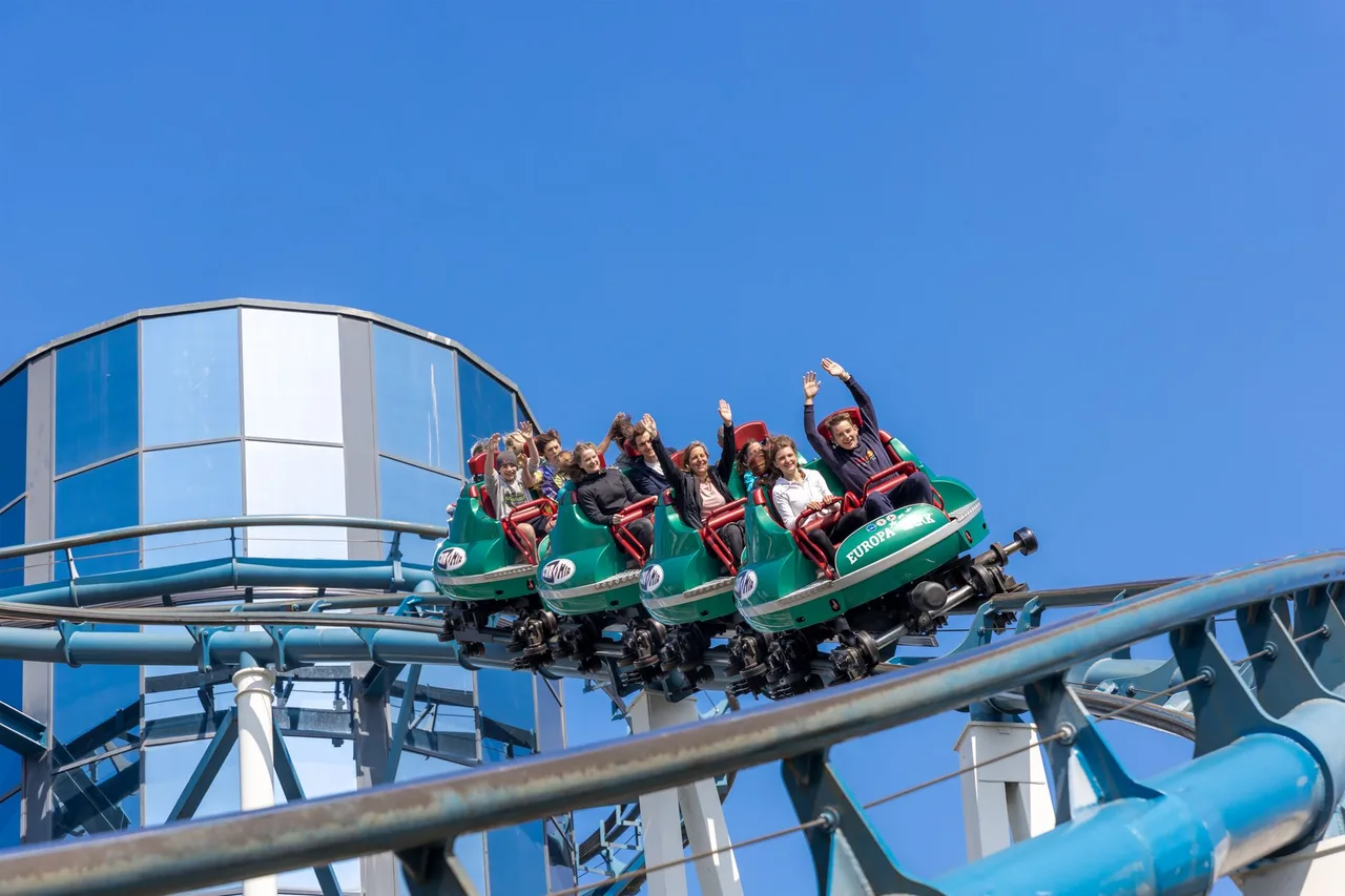 IMG Worlds of Adventure: největší krytý zábavní park světa Rodina s rozpaženýma rukama křičí radostí na horské dráze v zábavním parku