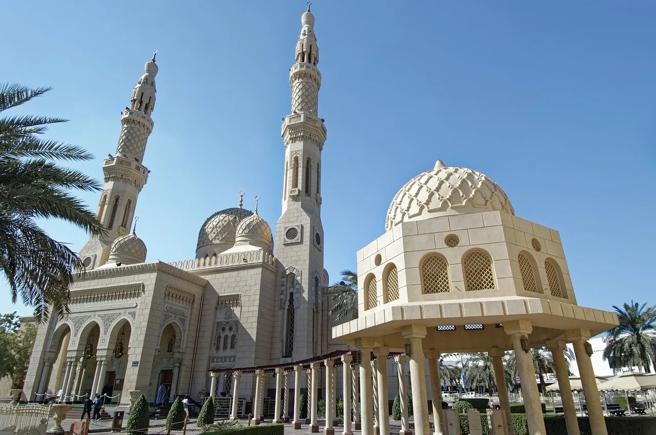 Jumeirah Mosque: návštěva jediné mešity v Dubaji otevřené turistům Pískovcový komplex Jumeirah Mosque s minarety a majlisem, obklopený palmami