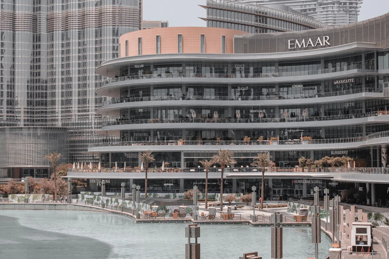 Dokončená budova developera Emaar s obchody a palmami u vodní plochy v Dubaji