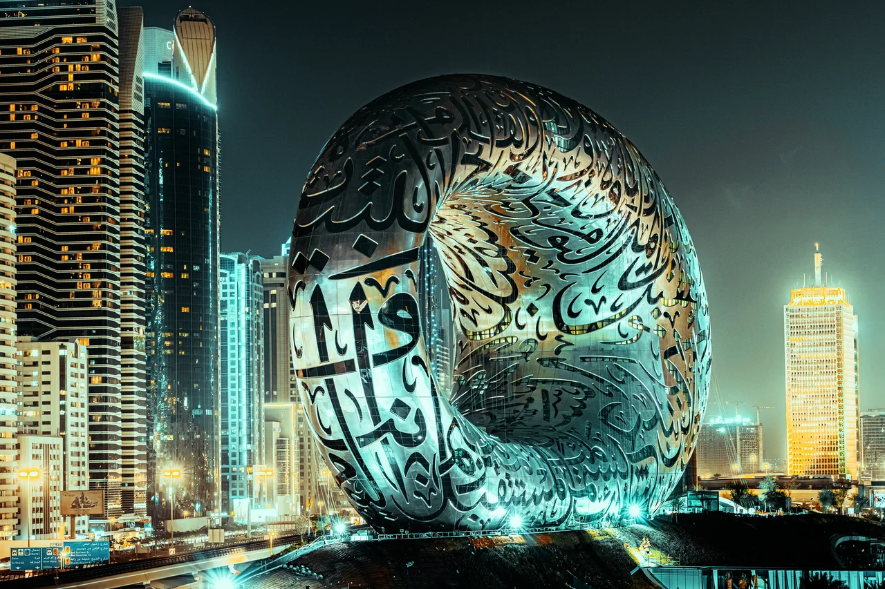 Nasvícená budova Museum of the Future v noci na pozadí panoramatu Dubaje